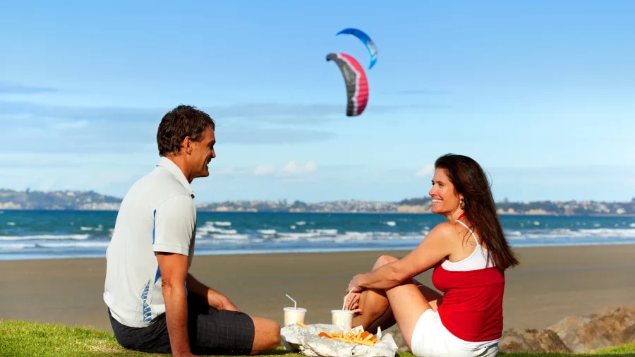 Couple eating fish and chips at Orewa Beach