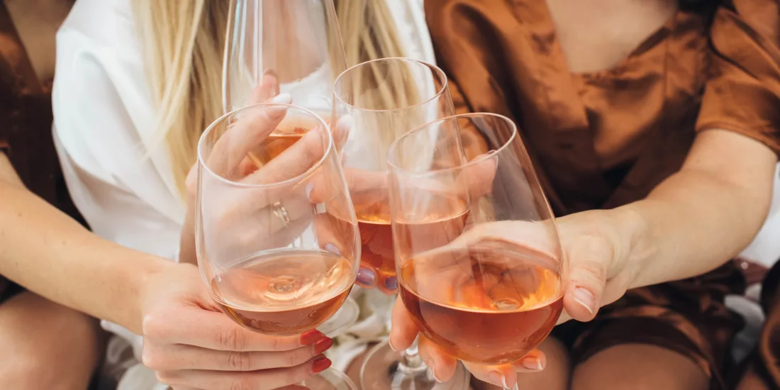 Close-up of a group of friends clinking glasses of rosé wine in a joyful celebration, showcasing a moment of connection and elegance.