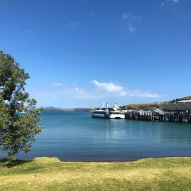 The ferry arriving at Matiatia Wharf on Waiheke Island, with clear blue waters and scenic coastal views.