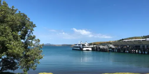 The ferry arriving at Matiatia Wharf on Waiheke Island, with clear blue waters and scenic coastal views.