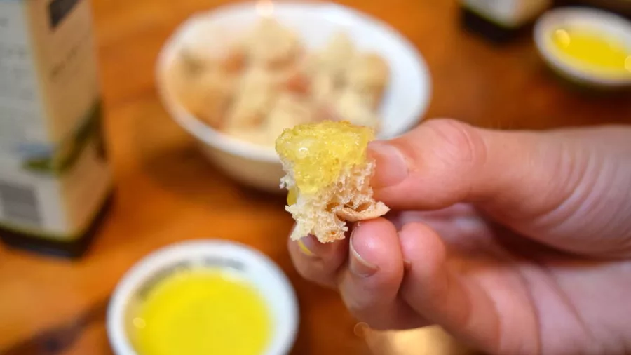 A guided Waiheke Island olive oil tasting experience with Ananda Tours, featuring artisan oils and fresh bread on a rustic wooden table.