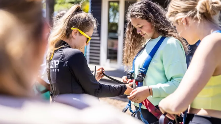 EcoZip Waiheke staff fitting harnesses during zipline safety briefing with guests in New Zealand