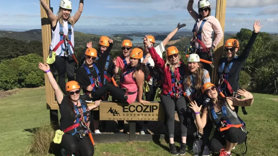 Private group celebrating at EcoZip Adventures Waiheke Island, equipped for ziplining with harnesses and helmets in scenic vineyard and forest surroundings