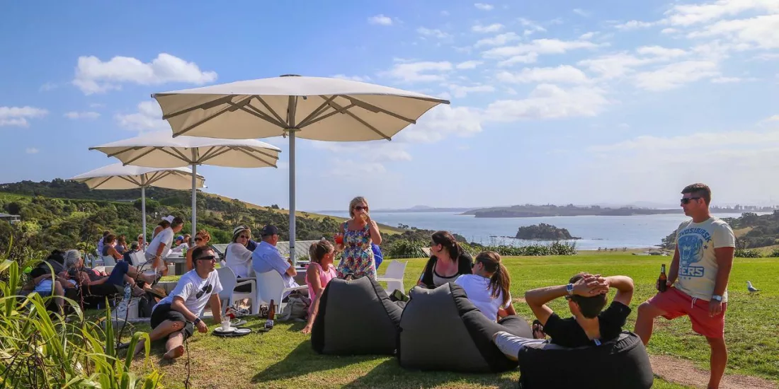 Guests at Cable Bay Vineyard on Waiheke Island enjoying wine tastings with panoramic coastal views during a premium EcoZip and wine tour