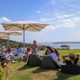 Guests at Cable Bay Vineyard on Waiheke Island enjoying wine tastings with panoramic coastal views during a premium EcoZip and wine tour