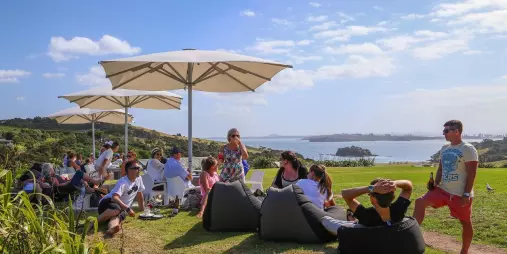 Guests at Cable Bay Vineyard on Waiheke Island enjoying wine tastings with panoramic coastal views during a premium EcoZip and wine tour