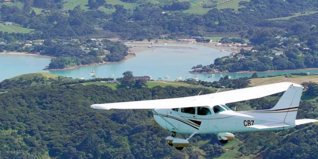 Cessna aircraft flying over Waiheke Island’s scenic coastal bays and green hills during an Island Aviation extended scenic flight tour from Auckland