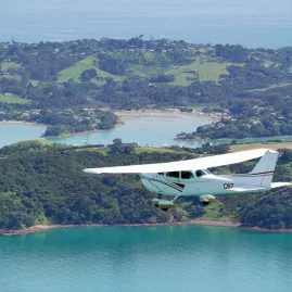 Cessna aircraft flying over Waiheke Island’s scenic coastal bays and green hills during an Island Aviation extended scenic flight tour from Auckland