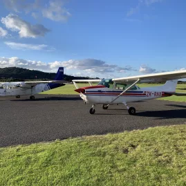 BN-2 Islander and Cessna aircraft parked on airfield grass at Waiheke Island, ready for scenic flights as part of the Island Aviation tour experience