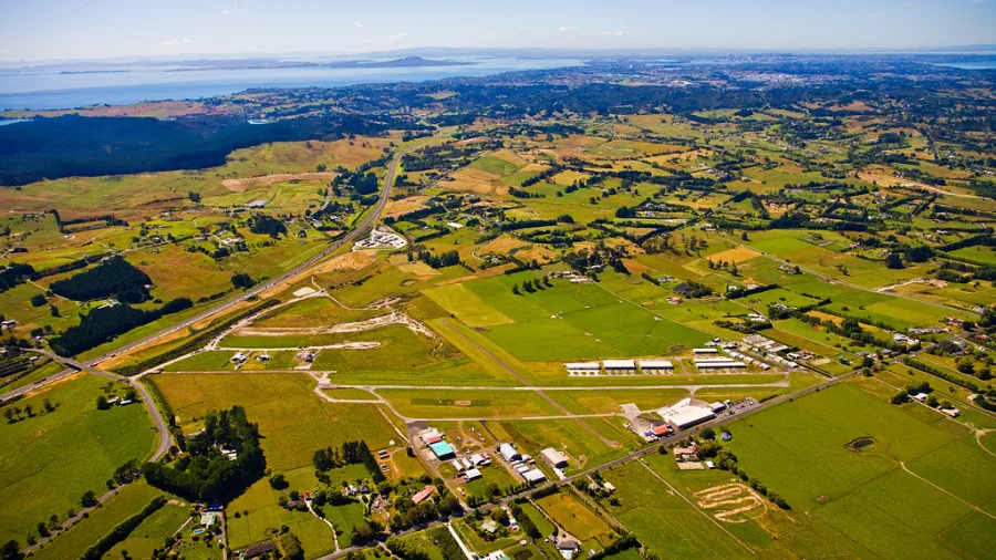 North Shore Airfield near Auckland with aircraft, grassy runways, and panoramic views toward Rangitoto Island, starting point for Island Aviation scenic flight to Waiheke