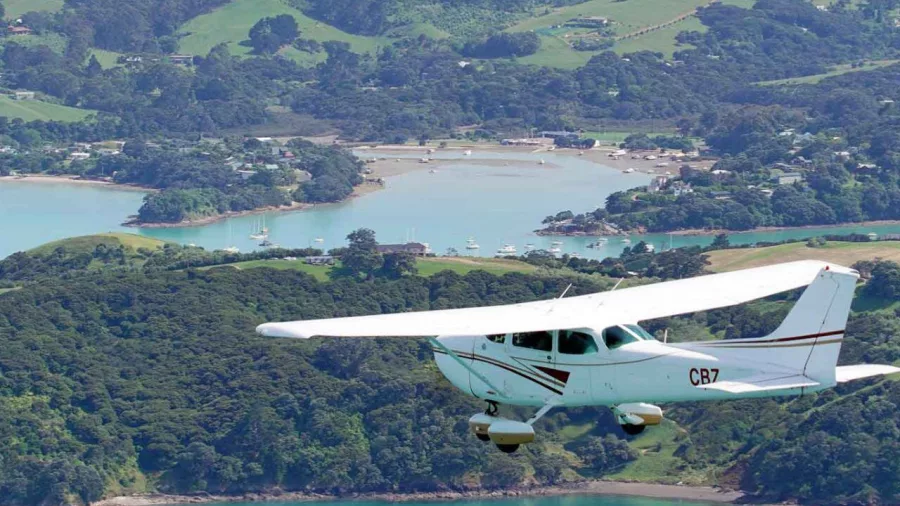 Cessna aircraft flying over Waiheke Island’s scenic coastal bays and green hills during an Island Aviation extended scenic flight tour from Auckland