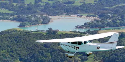 Cessna aircraft flying over Waiheke Island’s scenic coastal bays and green hills during an Island Aviation extended scenic flight tour from Auckland