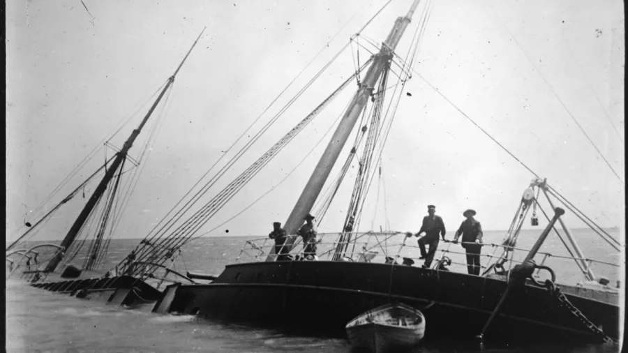 Historic SS Wairarapa shipwreck in shallow water off Great Barrier Island, New Zealand, with crew members onboard—site of a tragic 1894 maritime disaster.
