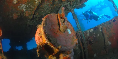 Diver swimming alongside a shipwreck during SSI wreck diving course