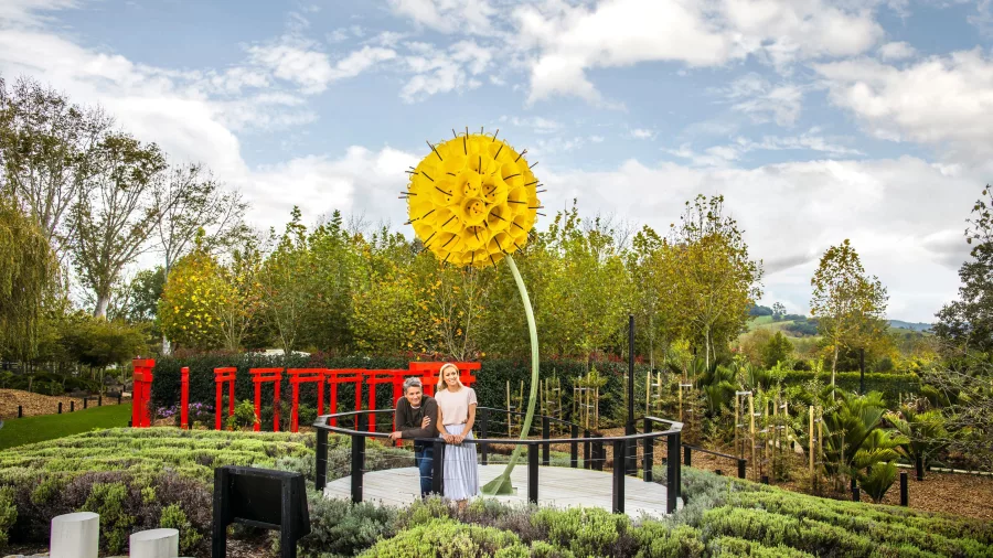 Bright yellow flower sculpture towering above guests in the garden at Sculptureum, Matakana, New Zealand.