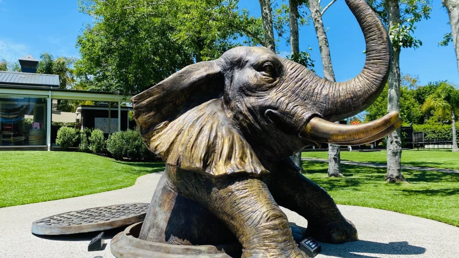 Bronze elephant sculpture emerging from manhole at Sculptureum gardens in Matakana