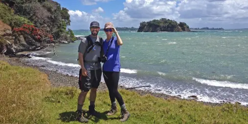 Hikers on the Waiheke Island Double Headland Walk with views over the coastline and offshore islands