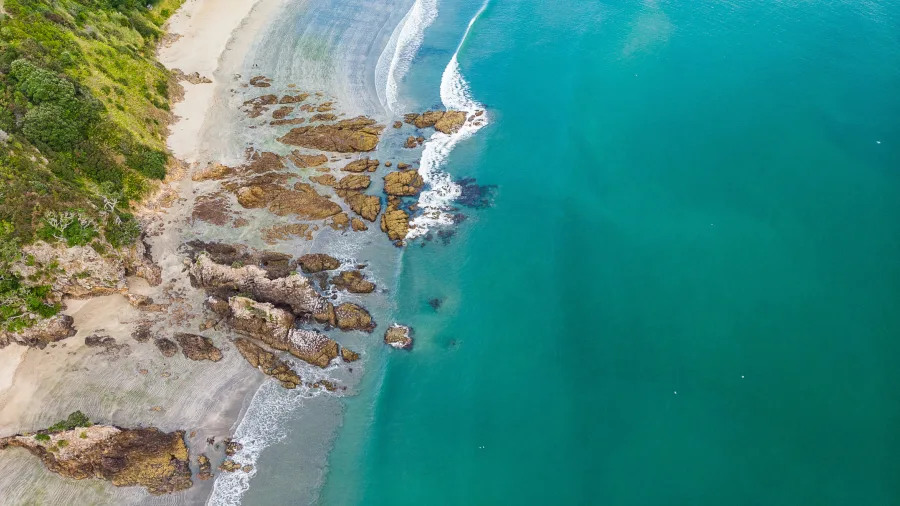Aerial view of rocky coastline and turquoise water on Waiheke Island