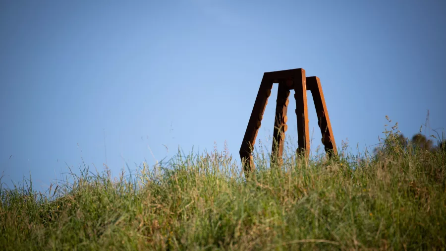 Large weathered metal sculpture by Anton Parsons on grassy hill at Brick Bay Sculpture Trail, Snells Beach New Zealand