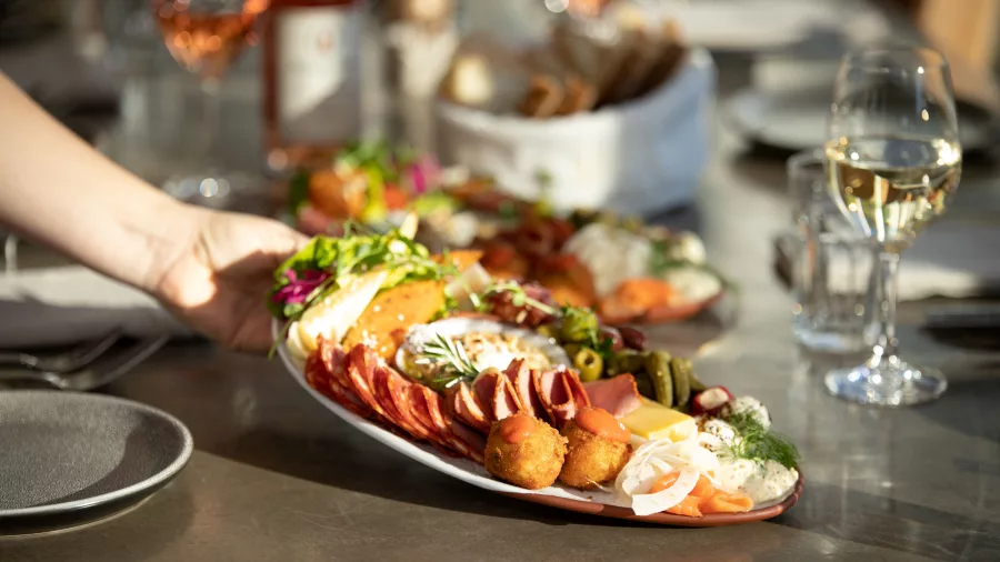 Gourmet sharing platter with artisan cheeses, charcuterie, and fresh produce served at Brick Bay in Snells Beach alongside wine