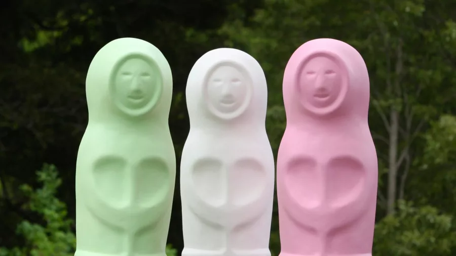 Simon Lewis Wards Eskimo sculptures in pastel green, white, and pink at Brick Bay Snells Beach, set against native bush