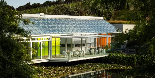 Brick Bay Glass House restaurant with sunlit glass walls overlooking the lake and gardens in Snells Beach