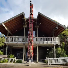 Entrance to Arataki Visitor Centre with carved pou and native bush backdrop
