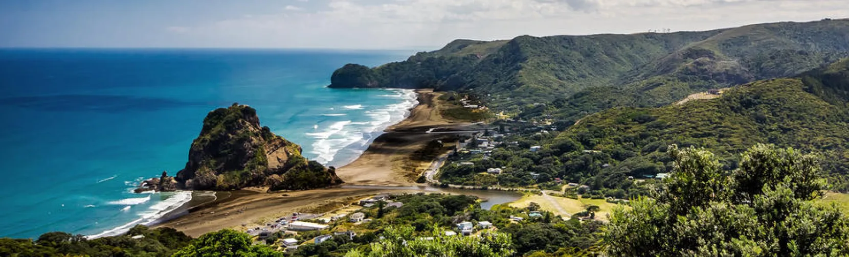 Piha Beach with black sand, powerful surf, and Lion Rock on New Zealand’s wild west coast