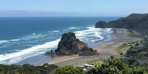 Rugged Piha coastline with black sand beach, sea cliffs, and crashing Tasman Sea waves on New Zealand’s west coast
