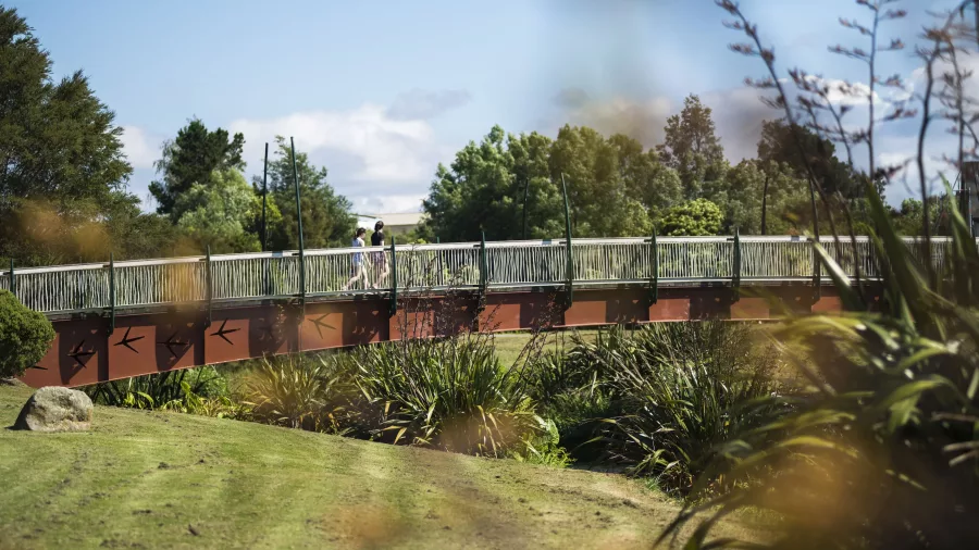 People walking across the Haiku Pathway footbridge surrounded by trees