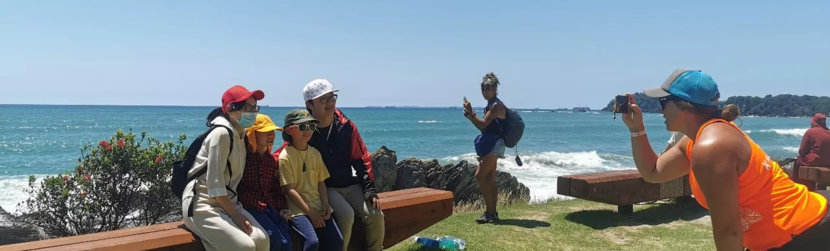 A guided group posing for a photo with coastal views at Mauao in Tauranga
