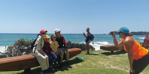 A guided group posing for a photo with coastal views at Mauao in Tauranga