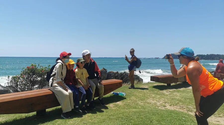 A guided group posing for a photo with coastal views at Mauao in Tauranga