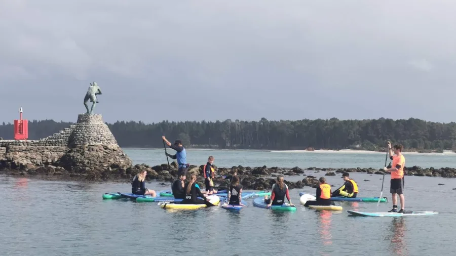 SUP group gathered near a waterside statue in Tauranga Harbour