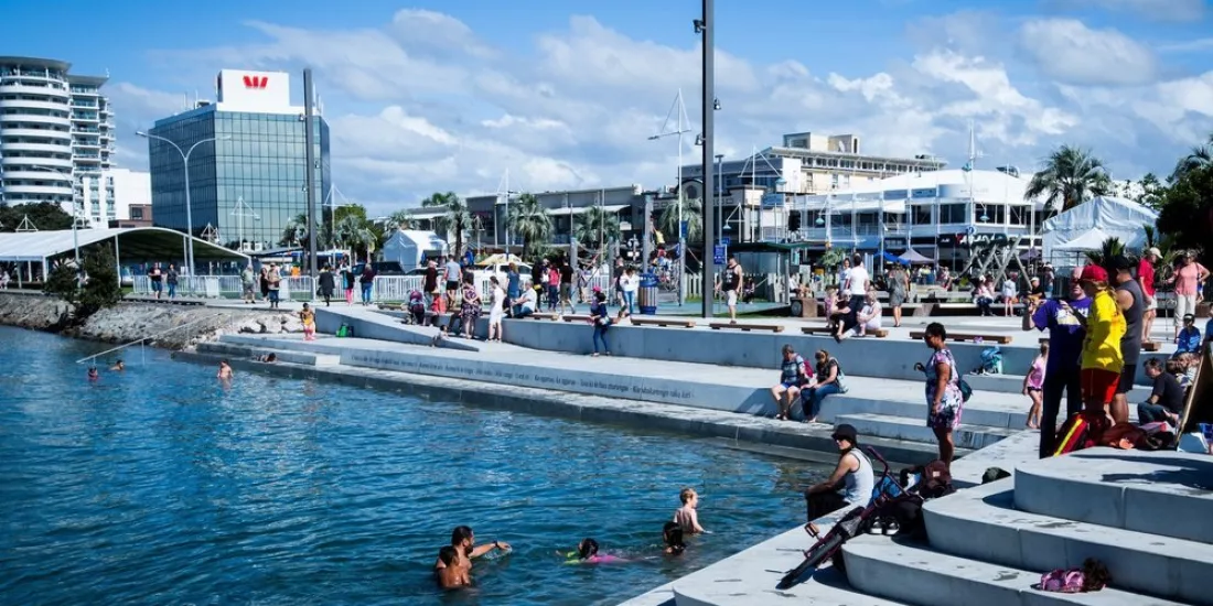 Locals and visitors enjoying the Tauranga waterfront with modern buildings in the background