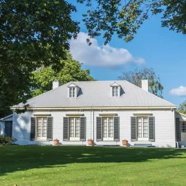 Historic Elms Mission House with white timber façade and lush lawn in Tauranga