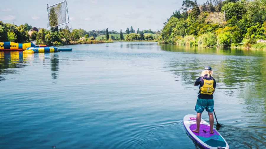 Paddleboarder approaches inflatable waterpark at Waimarino