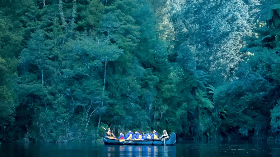 Group in a Big Kanu floating on still waters of Lake McLaren beneath dense forest