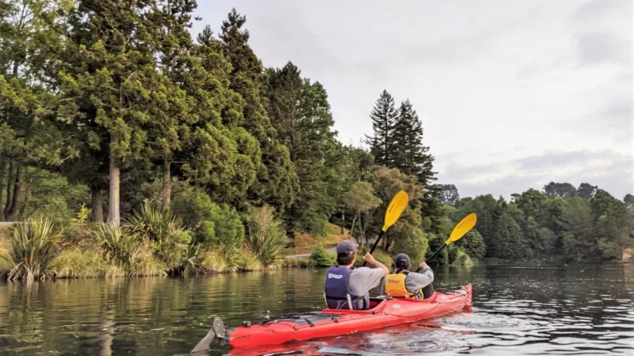 Two people kayaking on calm Lake McLaren surrounded by trees at sunset