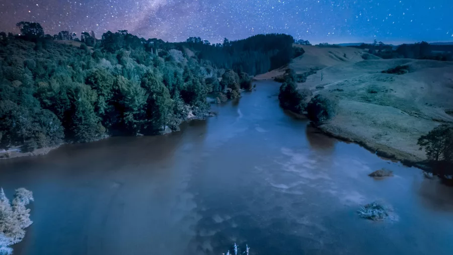 Aerial view of Lake McLaren under a star-filled night sky with kayakers below