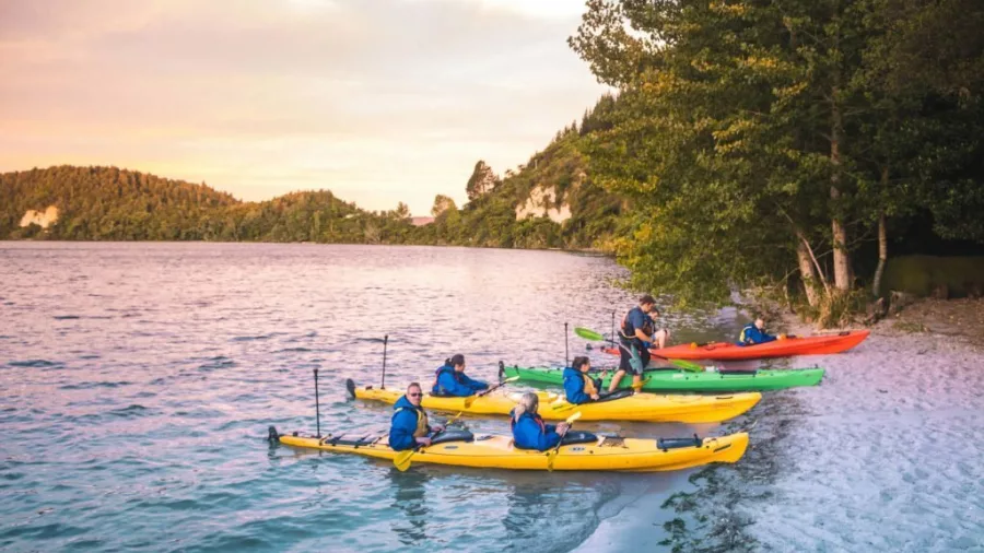 Kayakers bringing their boats to shore at sunset on Lake Rotoiti