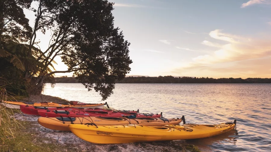 Colourful kayaks resting on the lake shore at sunset