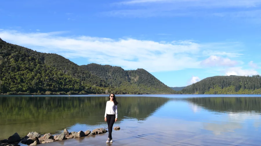 Woman walking along the shore of Blue Lake, also known as Lake Tikitapu, in Rotorua, New Zealand