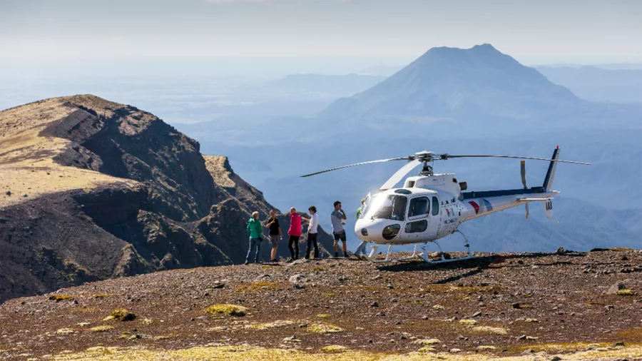 Helicopter and visitors on the summit of Mount Tarawera with volcanic landscapes in Rotorua, New Zealand