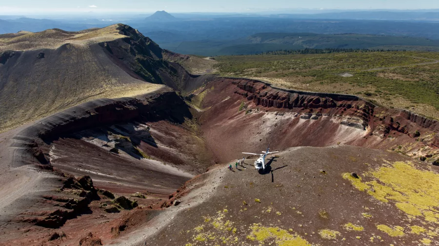 Aerial view of Mount Tarawera crater with helicopter and visitors, Rotorua, New Zealand