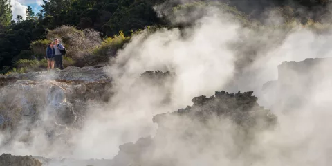 Couple viewing the dramatic steam clouds rising from Inferno Pool at Hell’s Gate Rotorua.