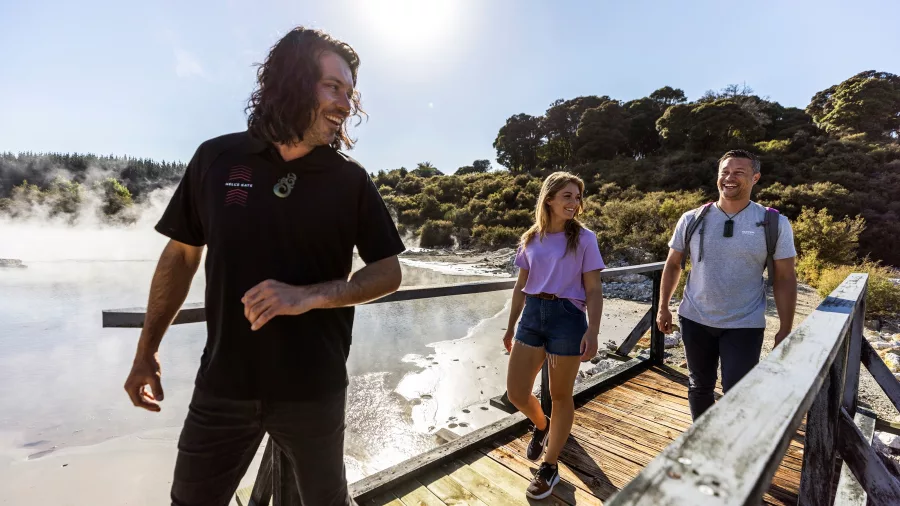 Visitors cross a wooden bridge through steam clouds during a geothermal walk at Hell’s Gate Rotorua.