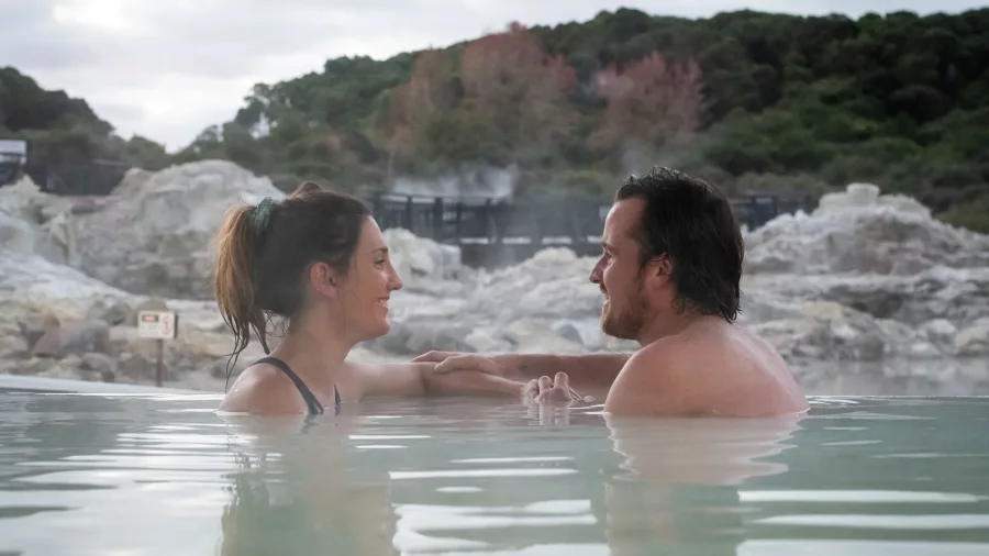 Couple soaking in a hot mineral pool surrounded by geothermal rocks at Hell’s Gate Rotorua.
