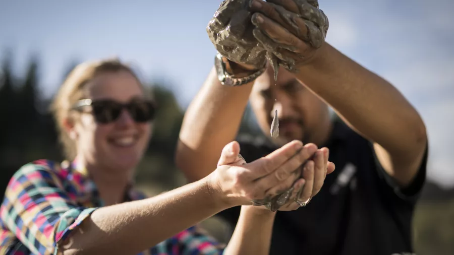 Guide demonstrating the healing properties of geothermal mud from Medicine Lake at Hell’s Gate.