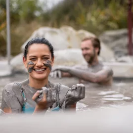 Woman smiling while enjoying a mud pool session at Hell’s Gate in Rotorua.